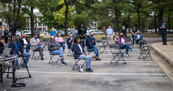 A crowd of people sit in chairs, socially distancing during the Grand Opening speeches.