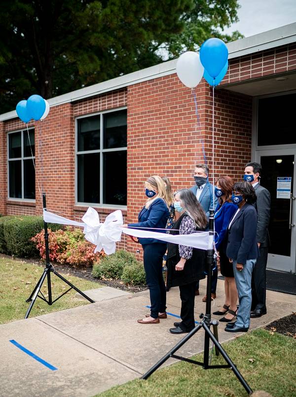 A group of UAFS administrators stand at the Writing Center front doors as Dr. Cammie Sublette and Dr. Monica Luebke cut a large white ribbon.