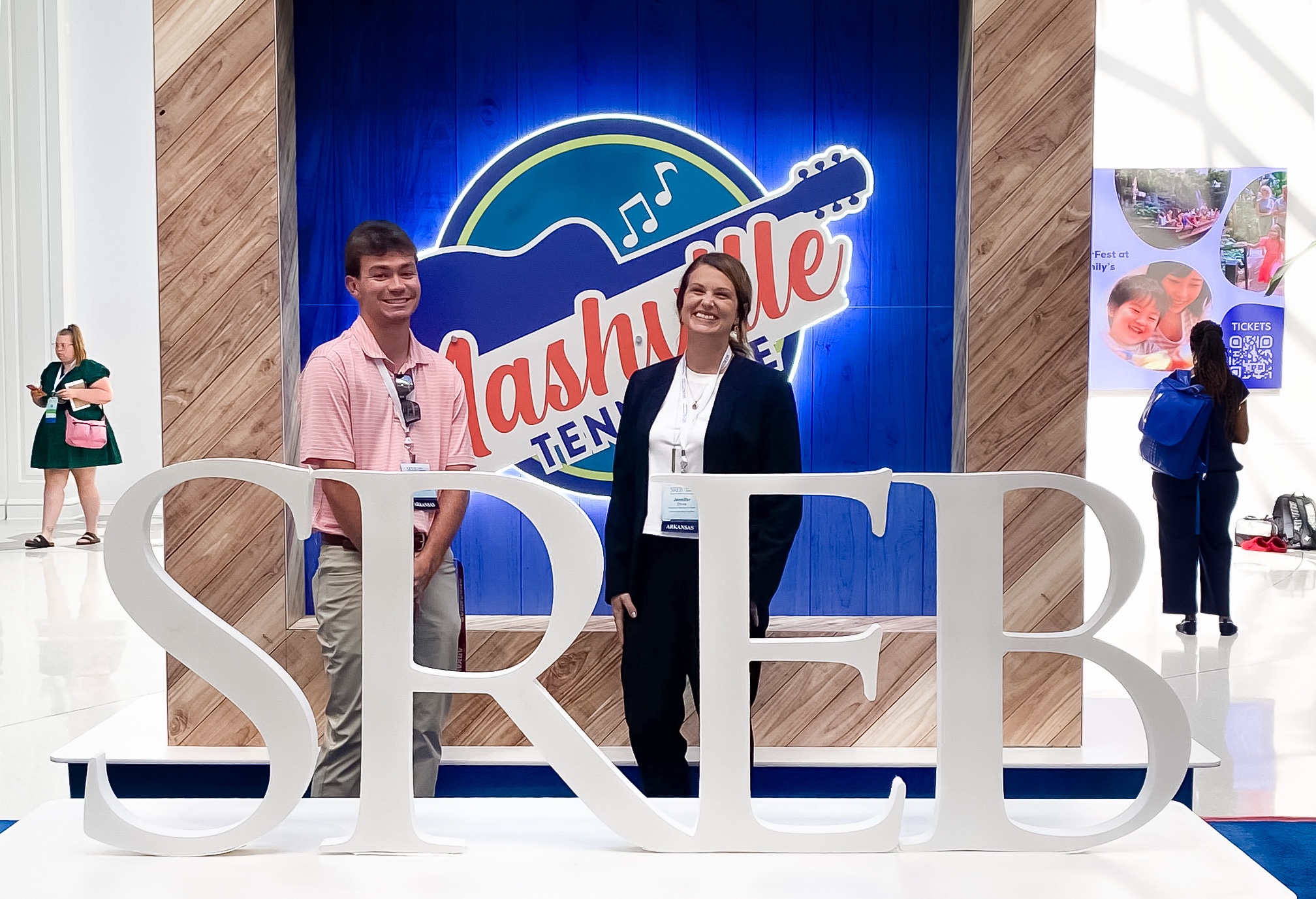 Student and professor stand in front of a sign in Nashville at a research symposium