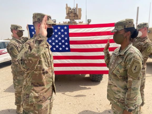 Shatoya Freeman salutes in front of an American flag