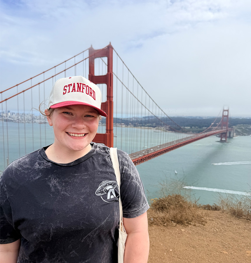 UAFS senior geosciences student, Abby Web, poses with the Golden Gate Bridge in the background while wearing a Stanford hat.