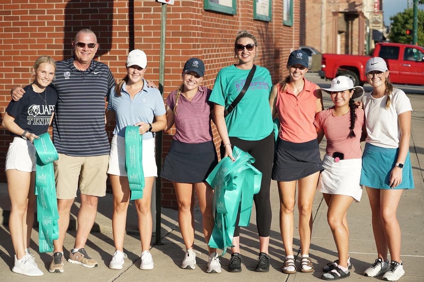 Beineke poses with student athletes during Turn the Town Teal