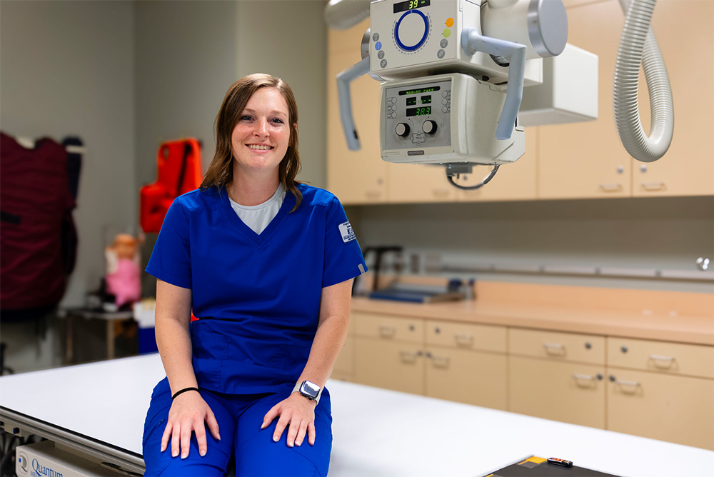 Callea Stewart sits on an imaging exam table in the Pendergraft Health Sciences Building.