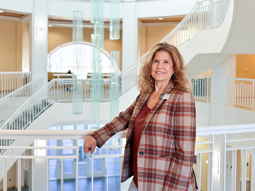 Dr. Cheryl Holden, executive director of the UAFS Master of Healthcare Administration program, stands on the second floor of the Pendergraft Health Sciences Building overlooking the lobby.