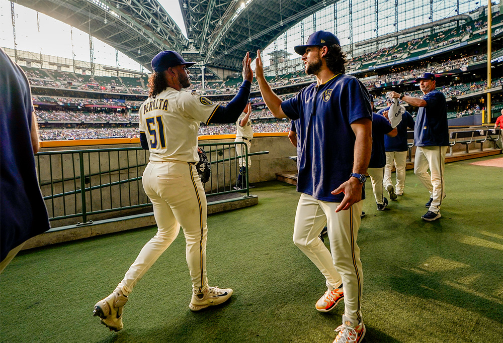 Daniel de Mondesert (right) high-fives Milwaukee Brewers pitcher Freddy Peralta in the Brewers stadium. Photo is courtesy of Scott Paulus/Milwaukee Brewers