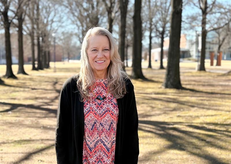 Janet Miller smiles on the UAFS Campus Green during a sunny winter day.