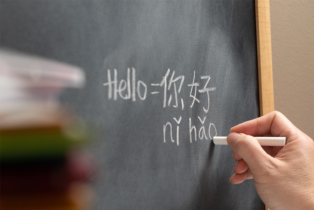 A chalkboard has the Mandarin translation of the English word "Hello" in characters and letters