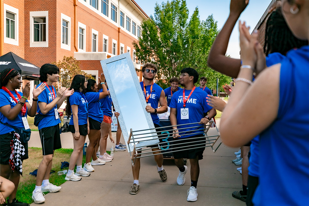 Students in Numa's Move-In Crew help carry items into the Lion's Den Residence Hall.