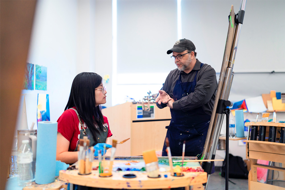 Peter Cullum (right) talks to a student during a modeling class